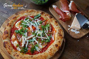 Pizza mit Parma­schin­ken, Ru­co­la und Par­me­san 