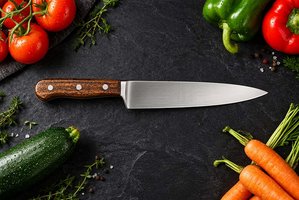 Deutsches Kochmesser mit frischem Gemüse auf Schiefer